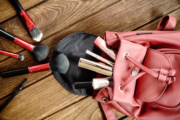 Bovenaanzicht van vrouwen tas spullen vrouwelijke cosmetische accessoires op woode - Foto, afbeelding
