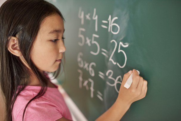 Focus girl trying to solve equation  - Фото, изображение