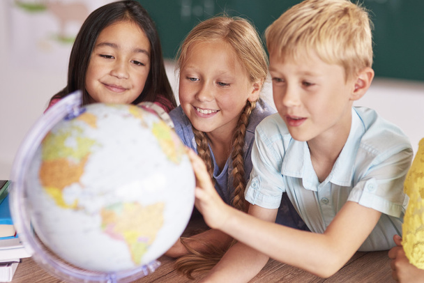 Ученики смотрят на земной шар на уроке
  - Фото, изображение