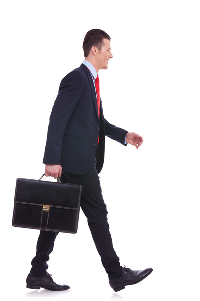 Side view επιχειρηματίας κρατώντας σύντομη υπόθεση και το περπάτημα - Φωτογραφία, εικόνα