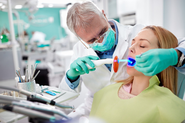 Dentist use dental instrument with light in dental work - Foto, imagen