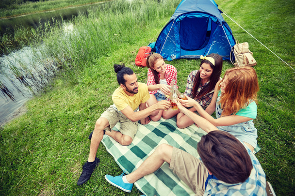 happy friends with tent and drinks at campsite - Photo, Image
