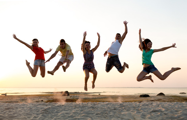amigos sonrientes bailando y saltando en la playa
 - Foto, imagen