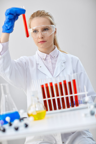 técnico químico serio sostiene tubos de ensayo con líquidos rojos
 - Foto, Imagen