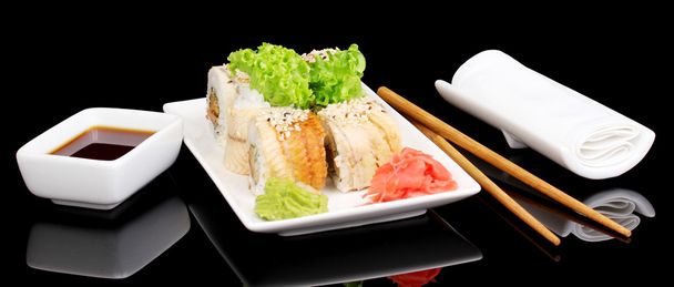 Tasty rolls served on white plate with chopsticks isolated on black - Foto, Imagen