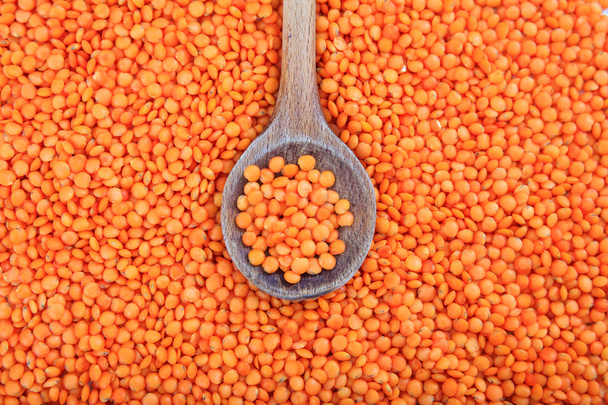 Wooden spoon on orange lentils background - Photo, Image