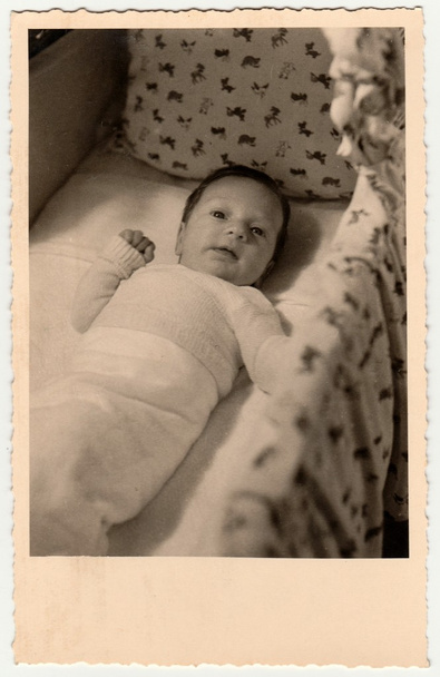  Foto vintage mostra bebê pequeno bonito em um berço (berço, cama de bebê). Retro preto & fotografia branca
. - Foto, Imagem