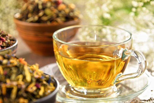 Composición con taza de té y tazones de hojas de té
 - Foto, Imagen