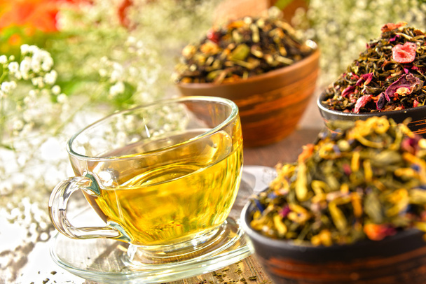 Composición con taza de té y tazones de hojas de té
 - Foto, Imagen