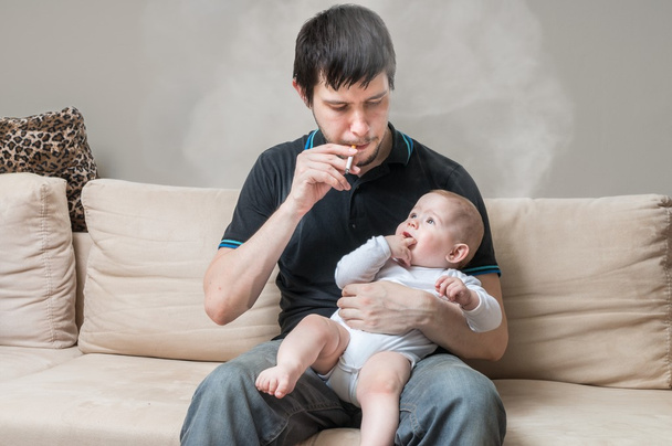 El padre fumador tiene un bebé. Concepto de padre malo
. - Foto, Imagen