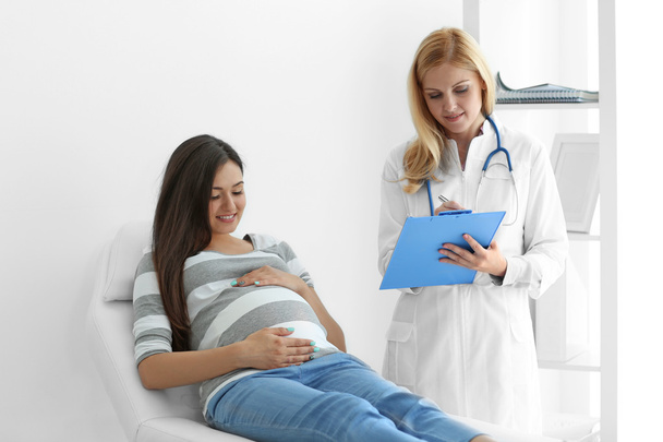 Young pregnant woman with doctor at the hospital - Foto, immagini