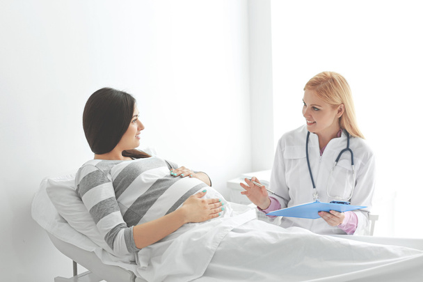 Young pregnant woman with doctor at the hospital - Foto, immagini