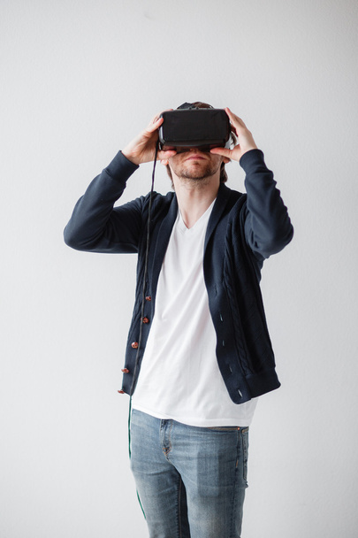 Przystojny mężczyzna nosi okulary wirtualnej rzeczywistości na białym tle na szarym tle - Zdjęcie, obraz
