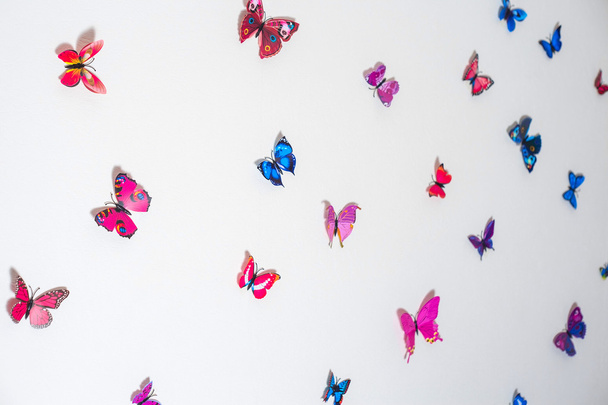Όμορφες τεχνητές πεταλούδες σε ένα φόντο λευκό τοίχωμα - Φωτογραφία, εικόνα