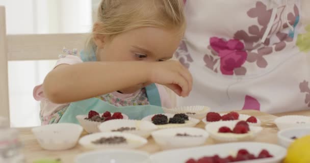 Child and woman preparing muffins on table - Footage, Video