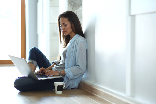 Young beautiful woman at home sitting on the floor with laptop - Foto, immagini