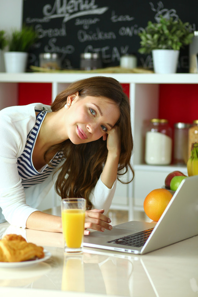 Young woman sitting near desk in the kitchen - Photo, image