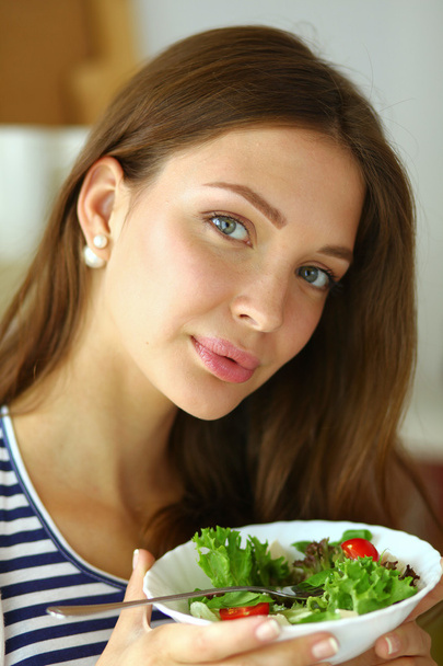 Mladá žena jíst salát a drží míchaný salát - Fotografie, Obrázek