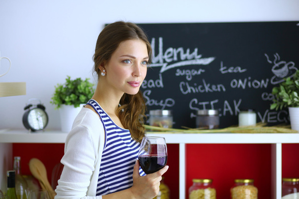 Pretty woman drinking some wine at home in kitchen . - Foto, Bild