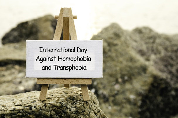Concepto de imagen con palabra DÍA INTERNACIONAL CONTRA LA HOMofobia Y LA TRANSPOBIA sobre lienzo blanco y caballete
.  - Foto, imagen