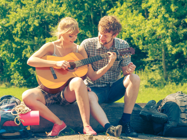Young couple camping playing guitar outdoor - 写真・画像