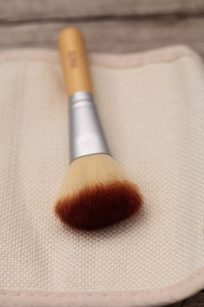 Cepillo de maquillaje sobre un fondo rústico texturizado
 - Foto, imagen