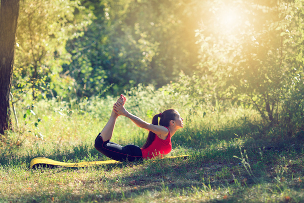 Adolescent faire du yoga et se détendre en s'asseyant dans une herbe dans un parc
 - Photo, image
