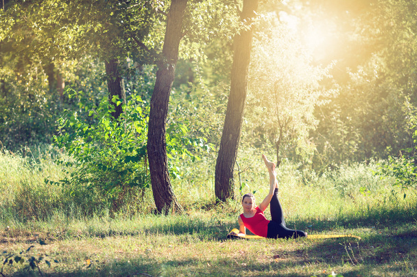 Teenager doing yoga and relaxing by siting in a grass in a park - Photo, image