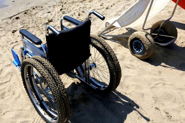 dos sillas de ruedas en la arena de la playa
 - Foto, Imagen