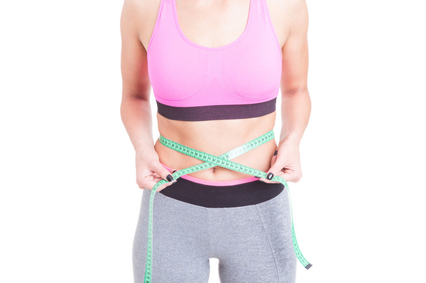 Fit woman holding tape line on waist - Foto, Bild