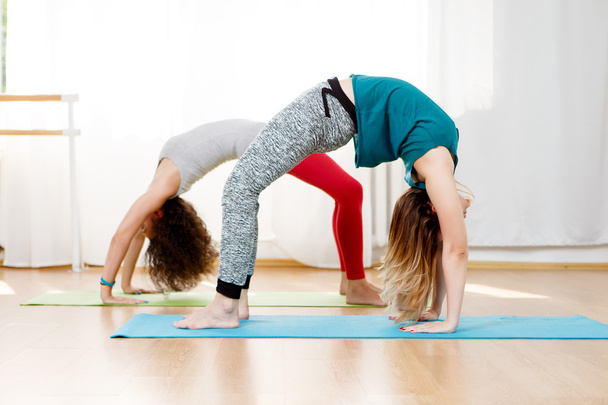 Flexible young women practice chakrasana asana in yoga studio - 写真・画像