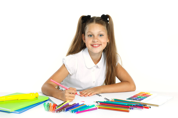 A beautiful girl in a school form drawing a marker, isolated on a white background - Photo, Image