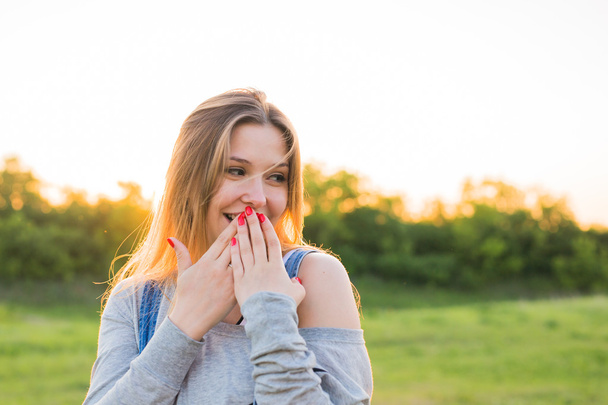 Surprised young woman with hands over her mouth outdoor - Photo, Image