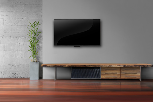 tv led su parete grigia con tavolo in legno in soggiorno
 - Foto, immagini