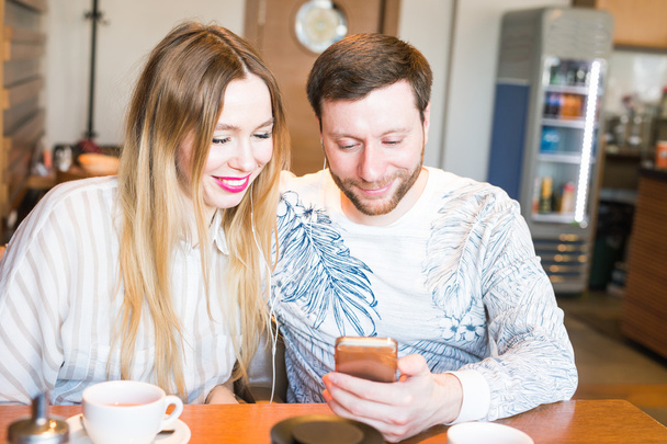 Casal feliz tomando café da manhã e fotografando-se - Amantes bonitos em um restaurante olhando para o celular
 - Foto, Imagem