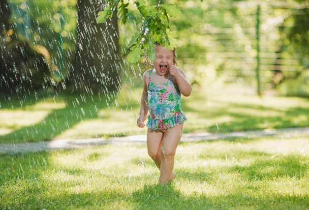 The little baby girl playing with garden sprinkler. - Zdjęcie, obraz