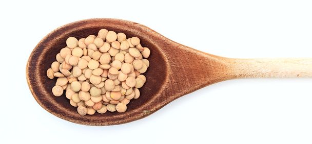 Raw lentils in a wooden spoon - Foto, afbeelding