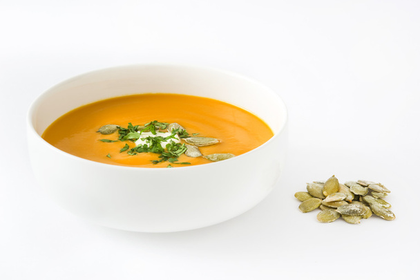 Тыквенный суп со сливками и тыквенными семечками на белом фоне
 - Фото, изображение