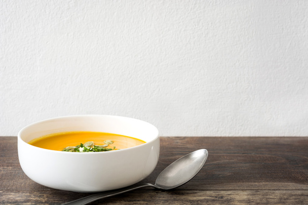 Тыквенный суп со сливками и тыквенными семечками на деревянном фоне
 - Фото, изображение