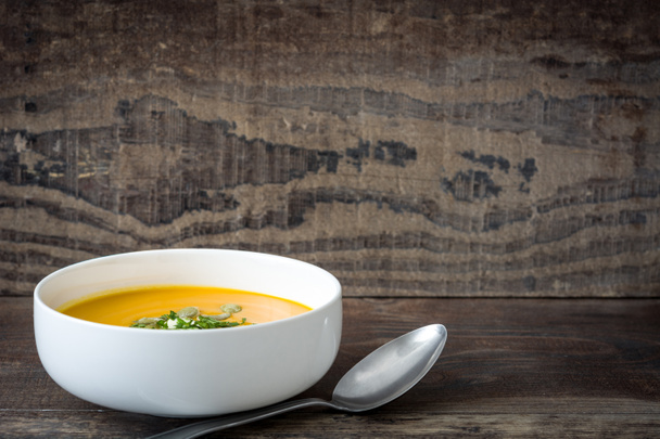 Pumpkin soup with cream and pumpkin seeds on wooden background - Photo, Image