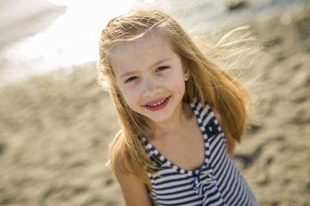 Cute little girl standing close to beach at sunset - Photo, image