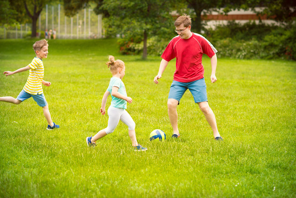 Happy family plays football in sunny park - Foto, afbeelding