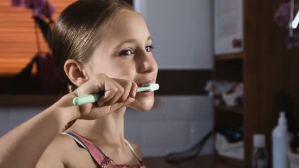 Niña en pijama rosa lavando y cepillando los dientes en el baño
 - Metraje, vídeo