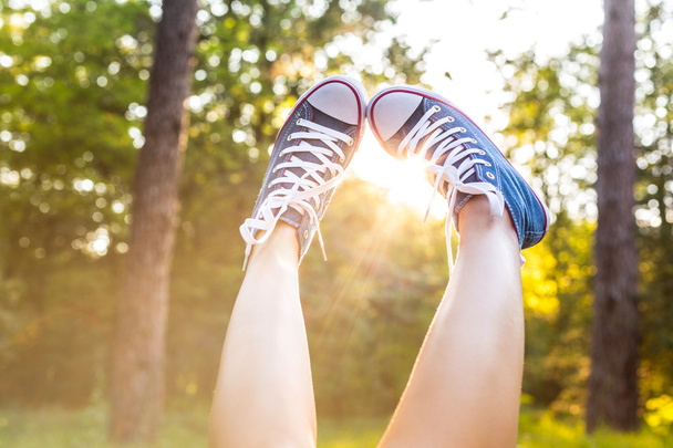 Günbatımı throug spor ayakkabılar bacaklar ışınları. - Fotoğraf, Görsel