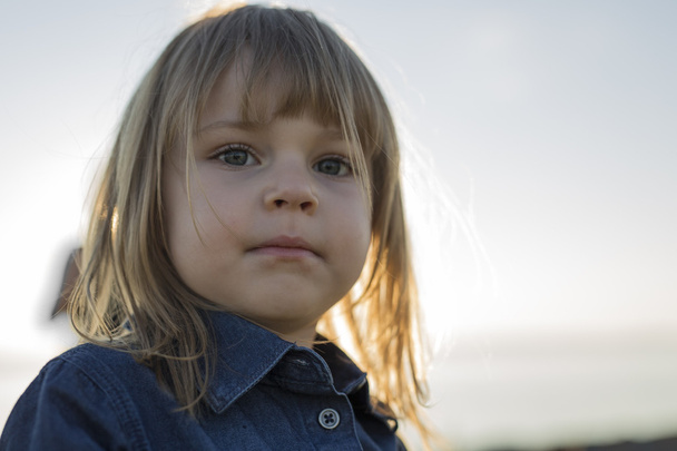 Cute little girl standing close to beach at sunset - Fotoğraf, Görsel