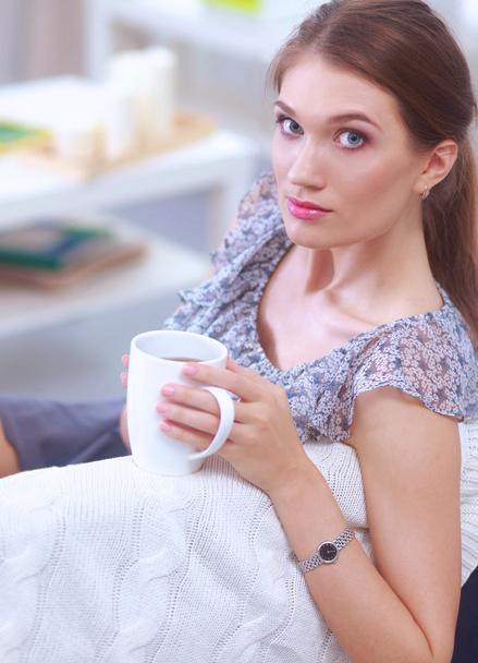 Portrait of young beautiful woman with a cup on sofa at home - Foto, immagini