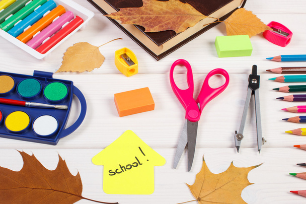 School accessories, shape of building and autumnal leaves on white boards - Photo, Image