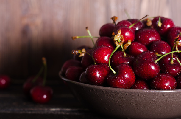 Cherries in a brown bowl on a wooden table. Free space for your text. - Фото, зображення