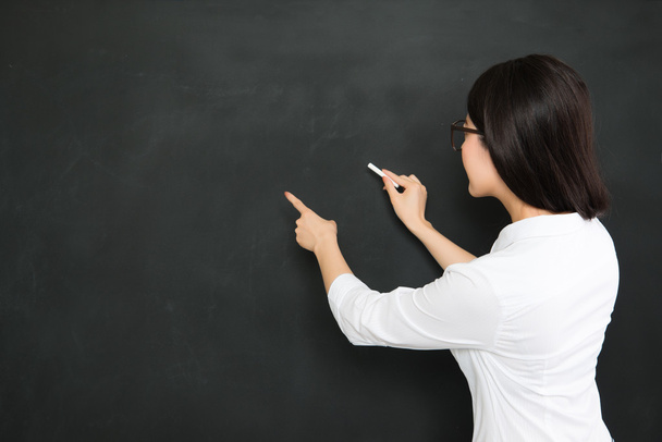 A good asian teacher writing question on blackboard with chalk - Foto, Imagem