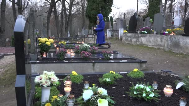 女性の膝の上と祈る家族の墓にろうそくを置きます。4 k - 映像、動画